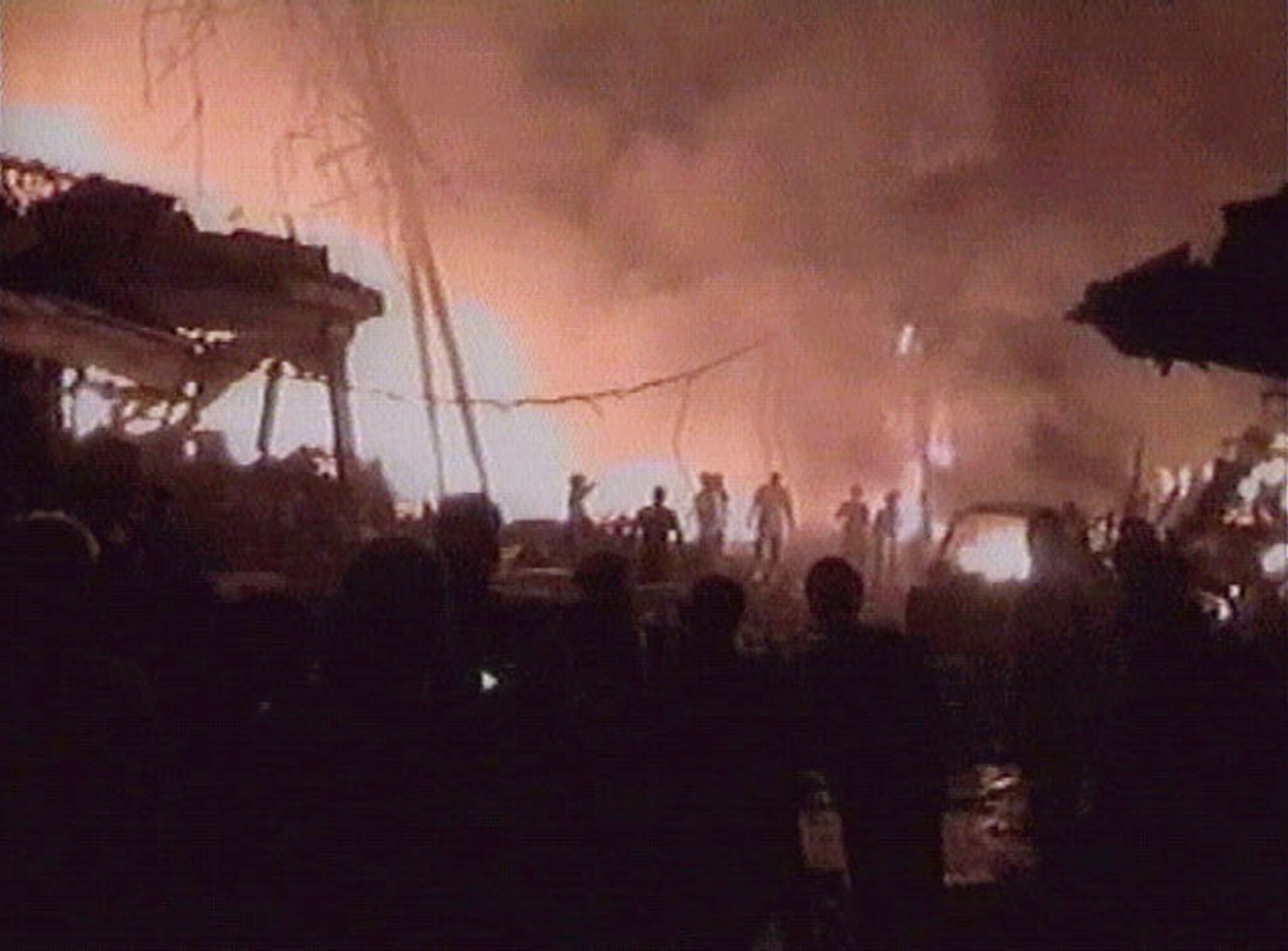 People当他们看到炸弹爆炸后建筑物和汽车残骸中燃烧的火焰时，可以看到剪影。” class=